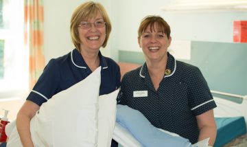 Two nurses making beds