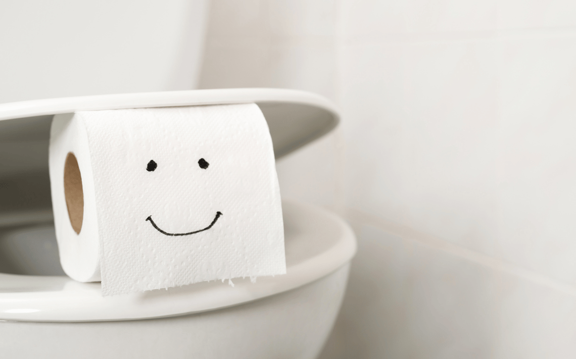 roll of toilet paper with smiley face balanced on toilet