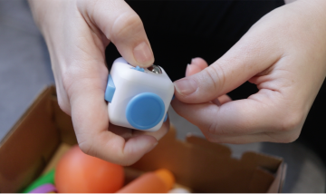 A close-up of someone playing with a fidget cube toy.