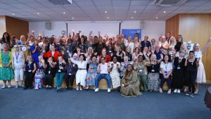 A group of around 70  people smiling and cheering at the camera at the Long Service Awards