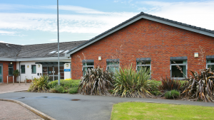 The Agnes Unit - a red brick single story building behind a path and grassed area. 