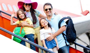 Family smiling boarding an airplane with bags