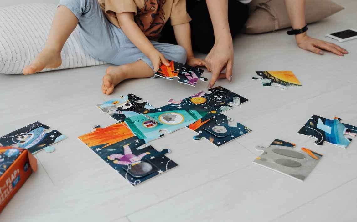 Parent and Child solving a puzzle on the floor.
