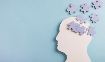 Silhouette of a side profile head with jigsaw puzzle pieces scattered