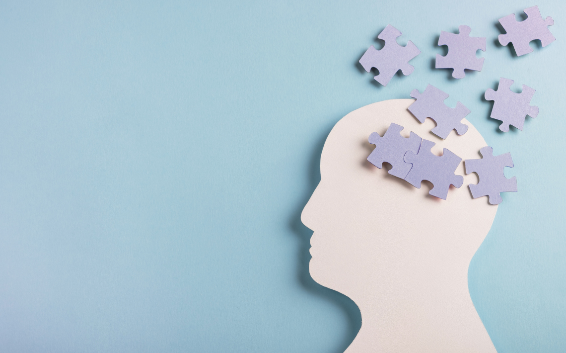 Silhouette of a side profile head with jigsaw puzzle pieces scattered