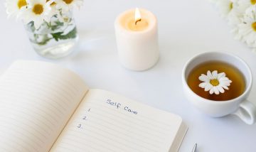 self care items including flowers candle, cup of tea and a note book