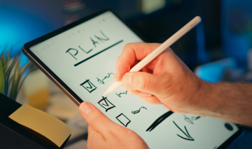 Hand held white board with 'Plan' tick list. Person's had shown ticking an item